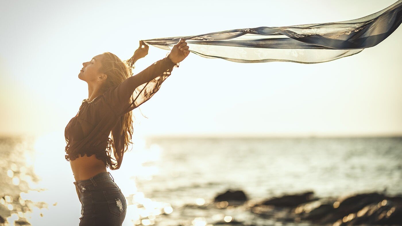 Woman with flag celebrating emotional freedom on the beach