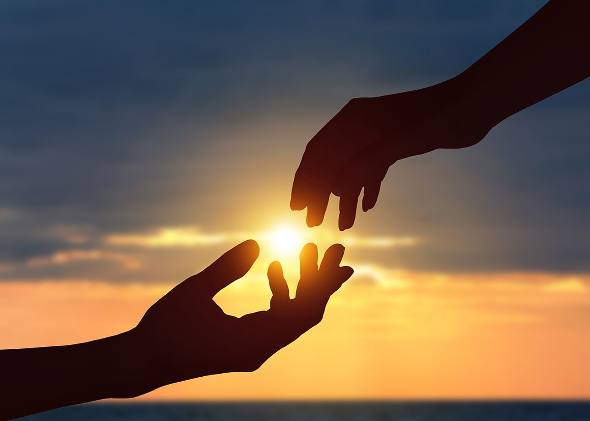 healthy hands reaching to each other at sunset